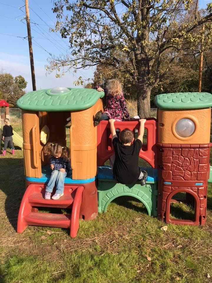 Three children playing on a colorful outdoor play structure