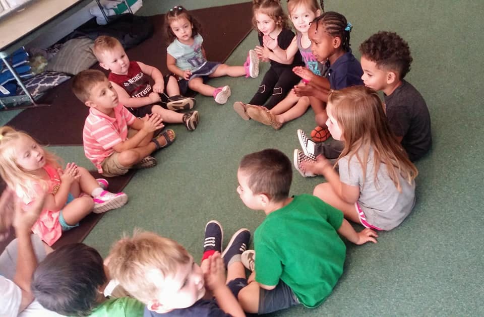 Many children sitting in a circle on the floor