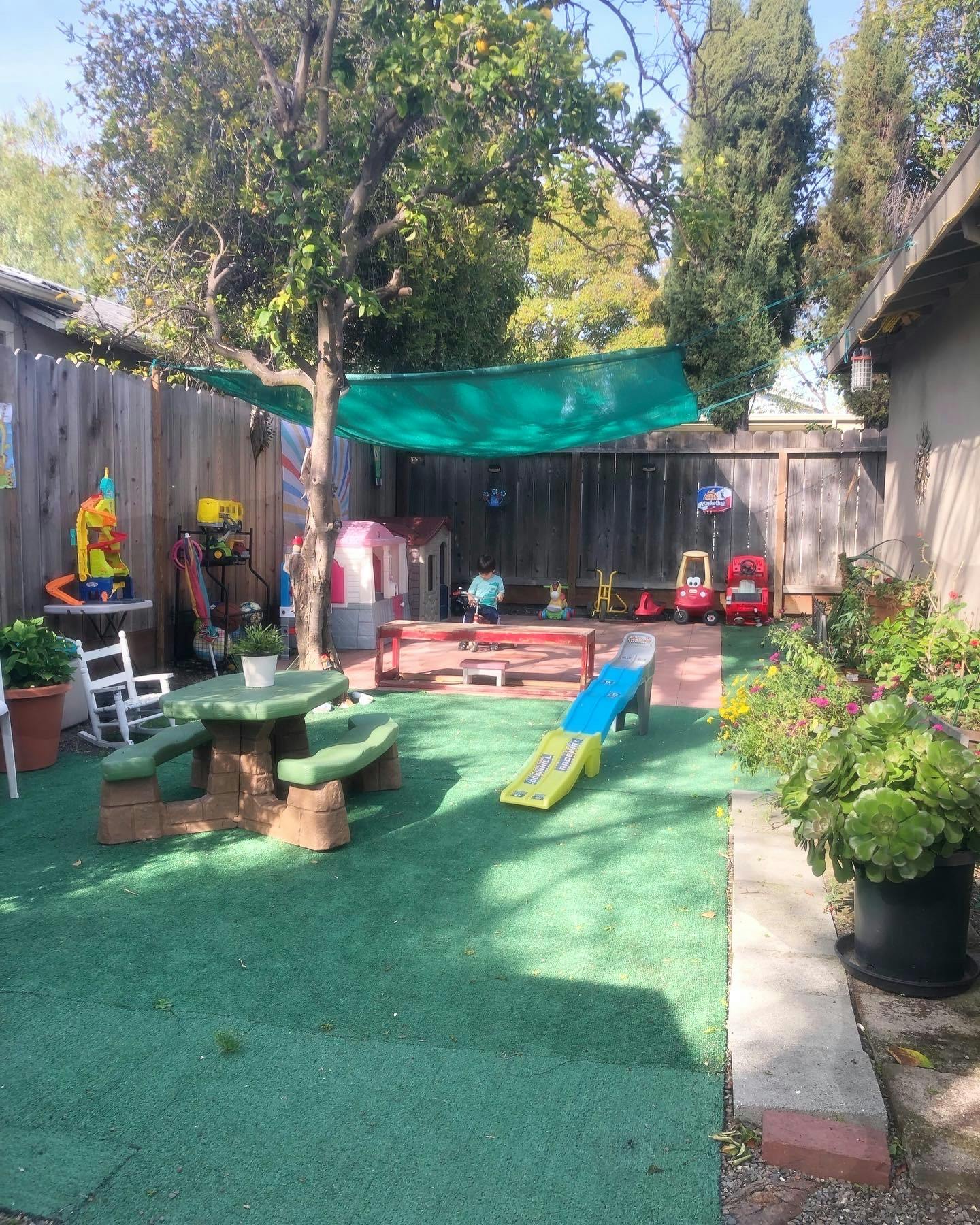 Backyard playground with artificial turf, picnic table, and slide
