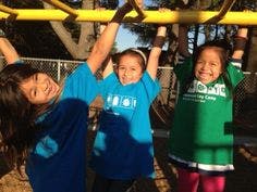 Three children hanging from monkey bars