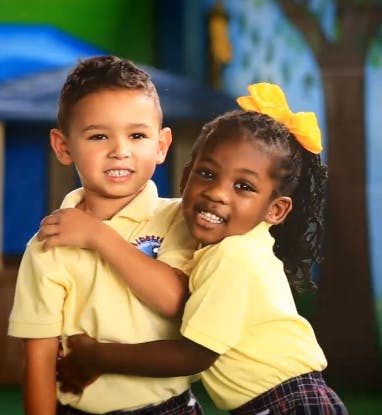 Two children in yellow shirts hugging