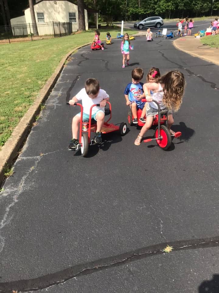 Children riding tricycles on pavement
