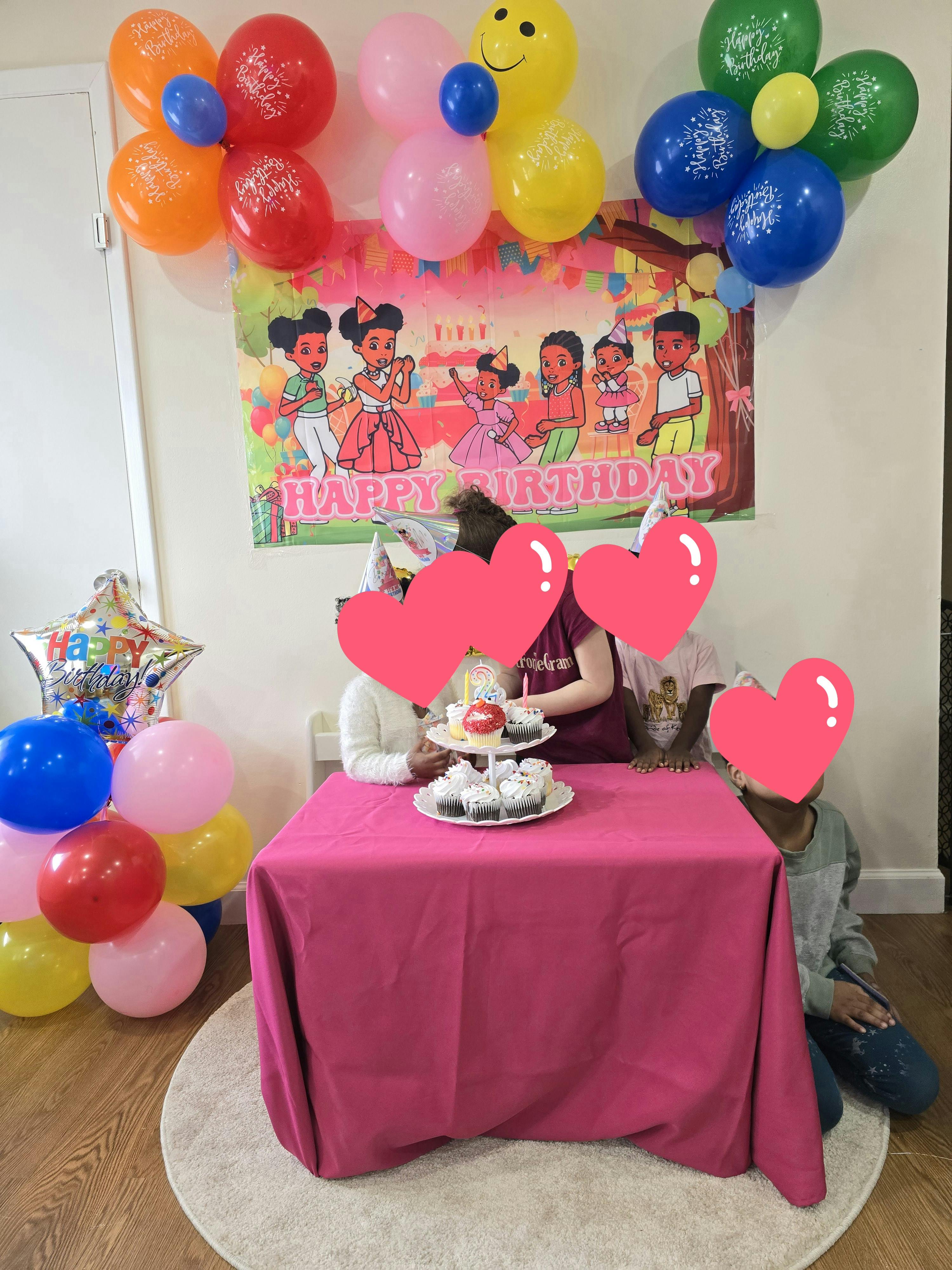 People gathered around a table with cupcakes and balloons