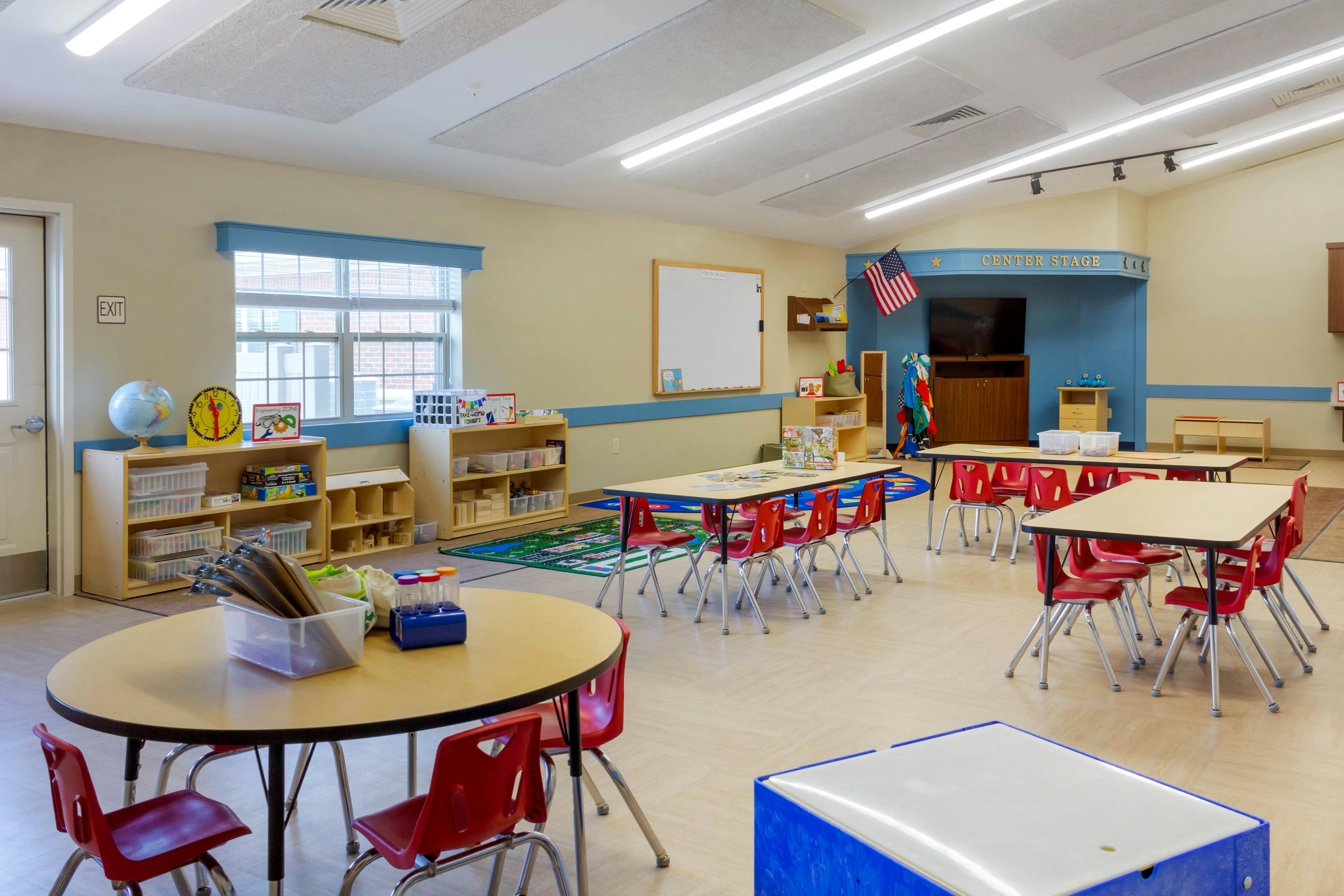Empty classroom with small tables and chairs, toys, and supplies