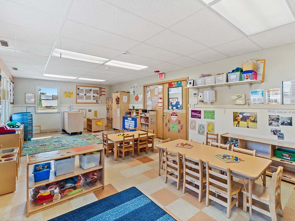 Empty colorful preschool classroom with small tables and chairs