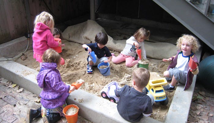 Children playing in a sandbox with toys