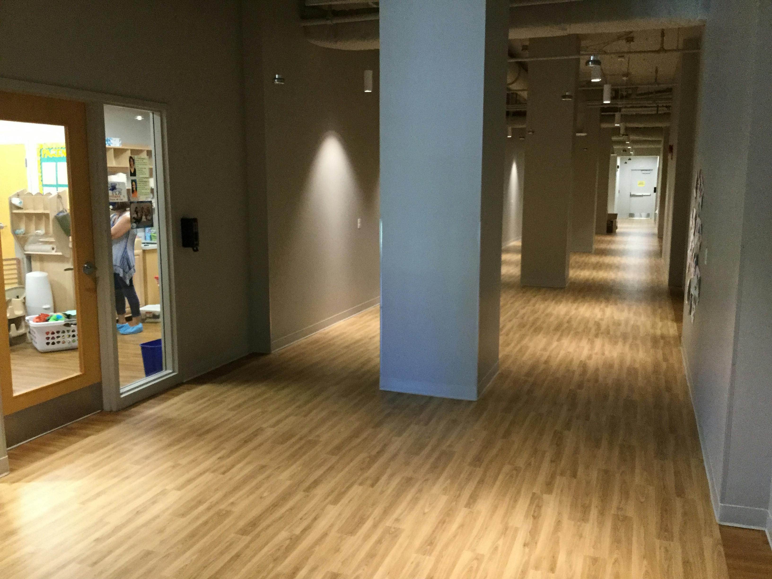 Long hallway with wood floor and a person visible through a doorway