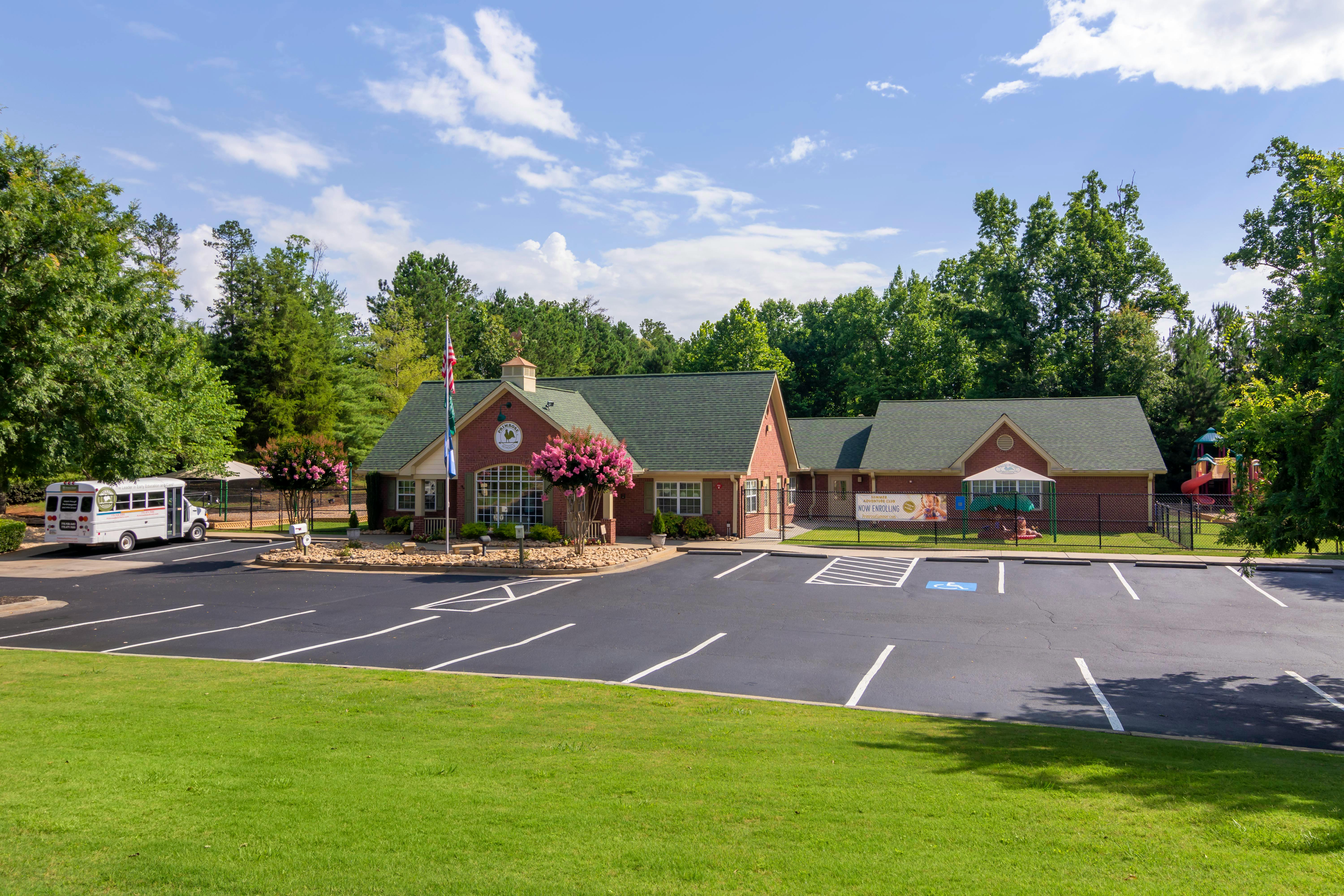 An aerial view of a brick school building with a parking lot and playground