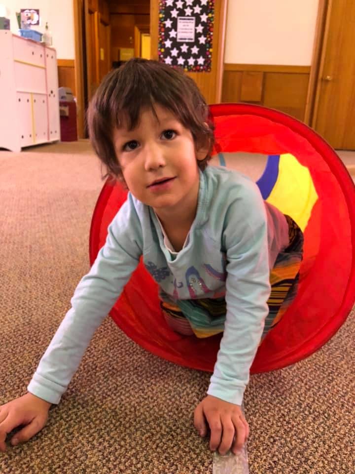 Child crawling through a red play tunnel