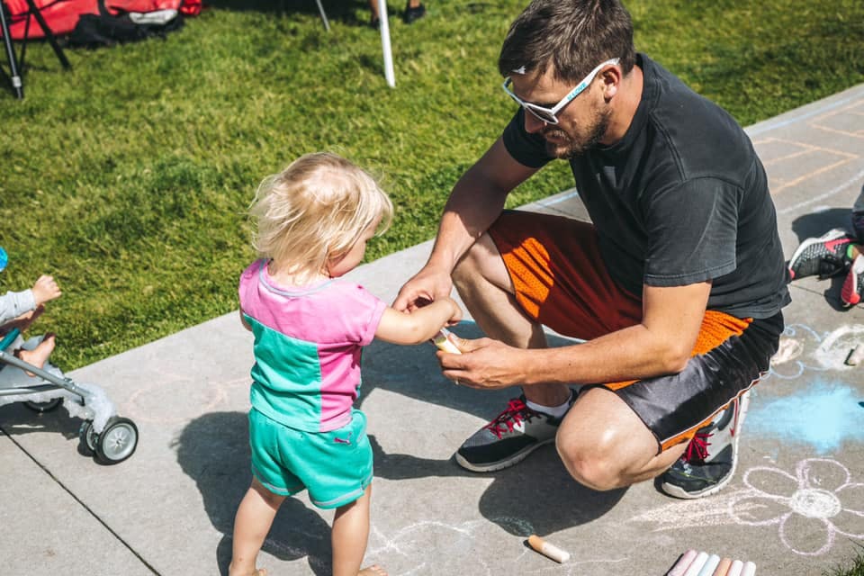 Adult person crouching and child standing on sidewalk