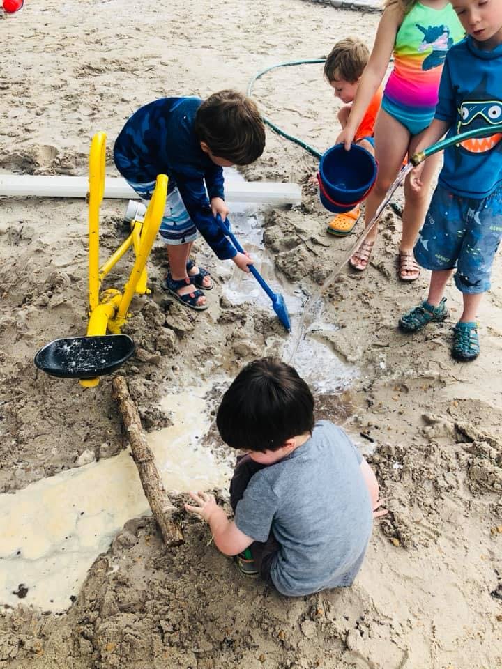 Children playing in sand with water and toys