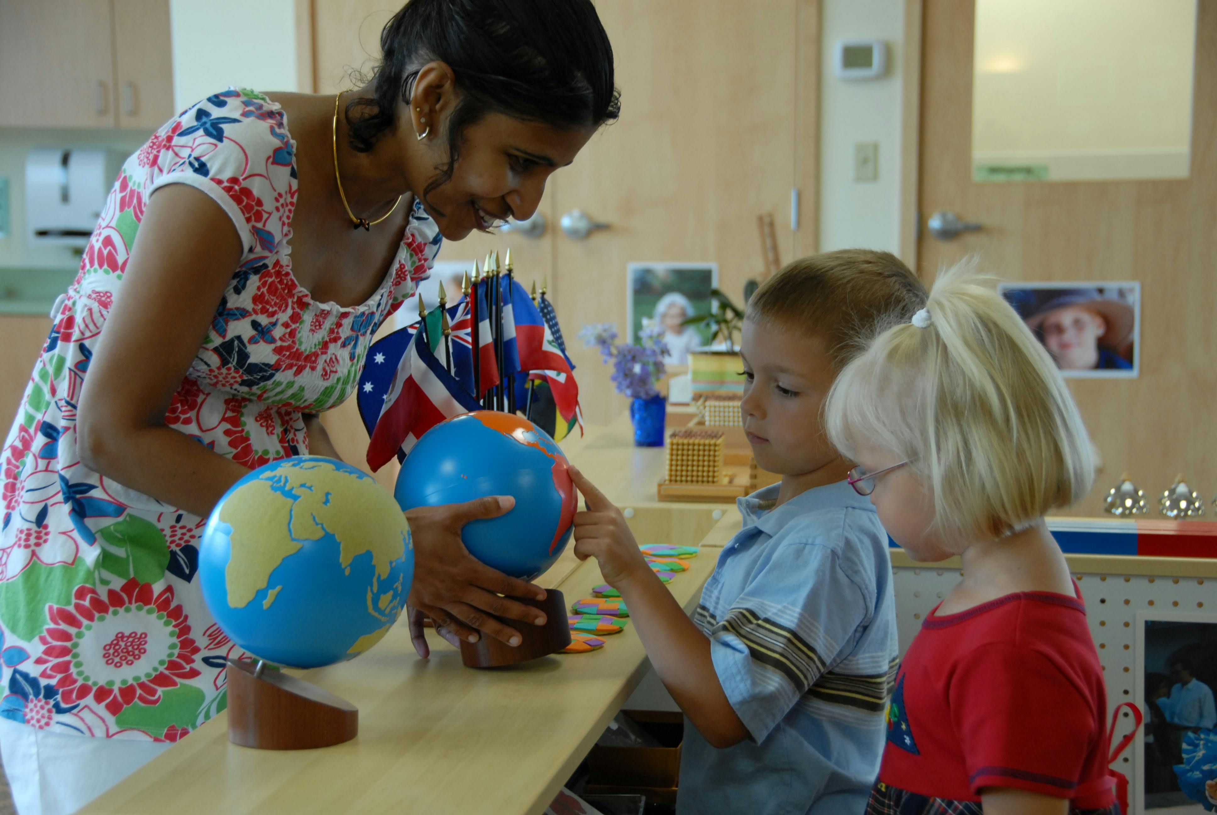 Person showing two children a globe in a classroom