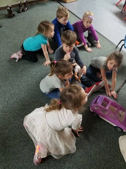 Group of children on a carpeted floor looking at toys