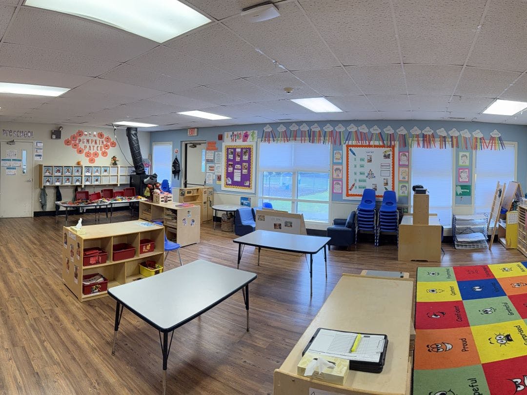 Empty preschool classroom with tables, chairs, and colorful decorations