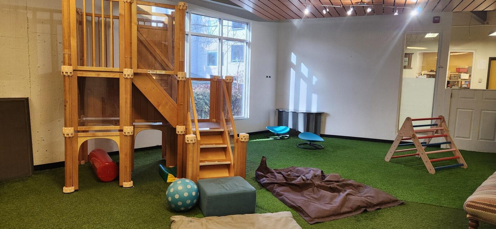 Indoor play area with wooden climbing structure on artificial turf