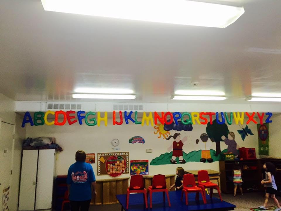Classroom with alphabet banner, wall mural, and person standing