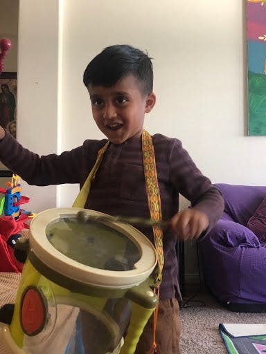 Child playing a toy drum with a drumstick