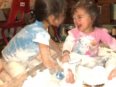 Two children playing in a pile of white powder