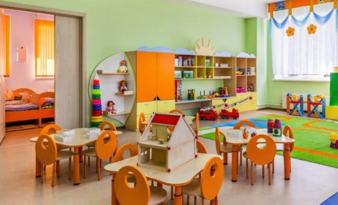 Playroom with small tables and chairs, shelves with toys, and a dollhouse
