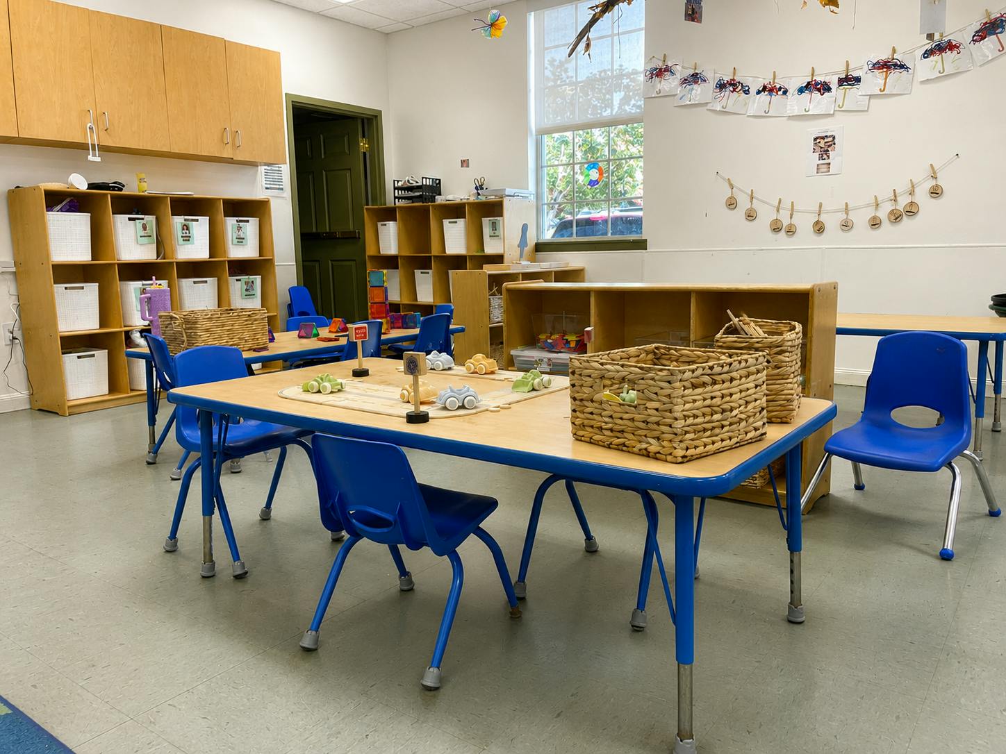 Classroom tables with small blue chairs and toy cars