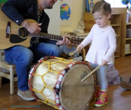 Person playing guitar next to a child playing a drum