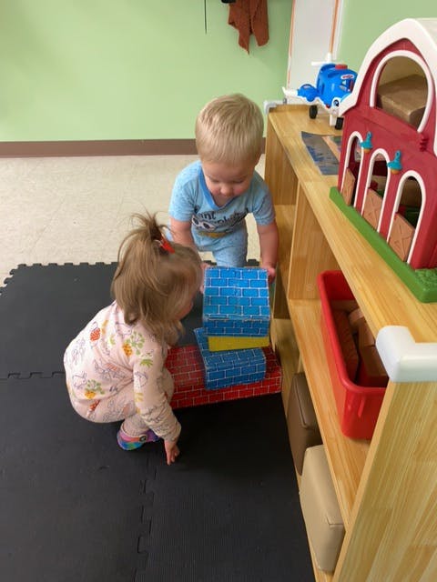 Two children playing with building blocks on the floor