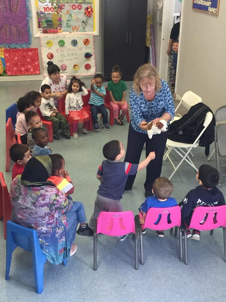 Adult holding a toy for children sitting in a classroom
