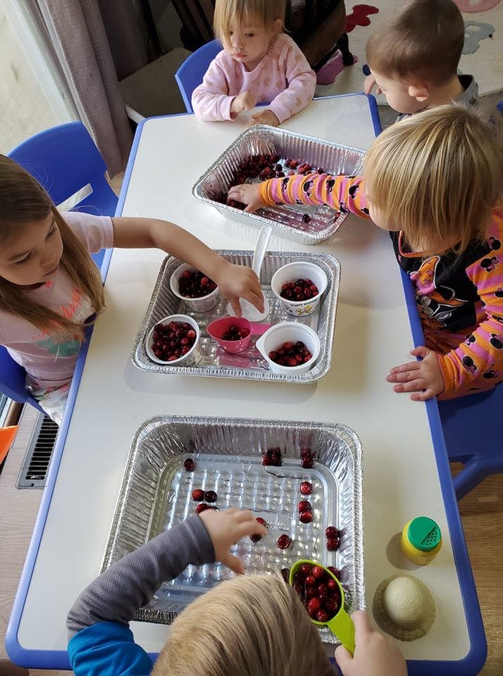 Children playing with berries in aluminum trays at a table