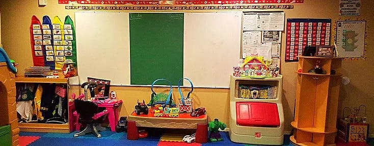 Classroom with whiteboard, green board, and various children's toys and furniture