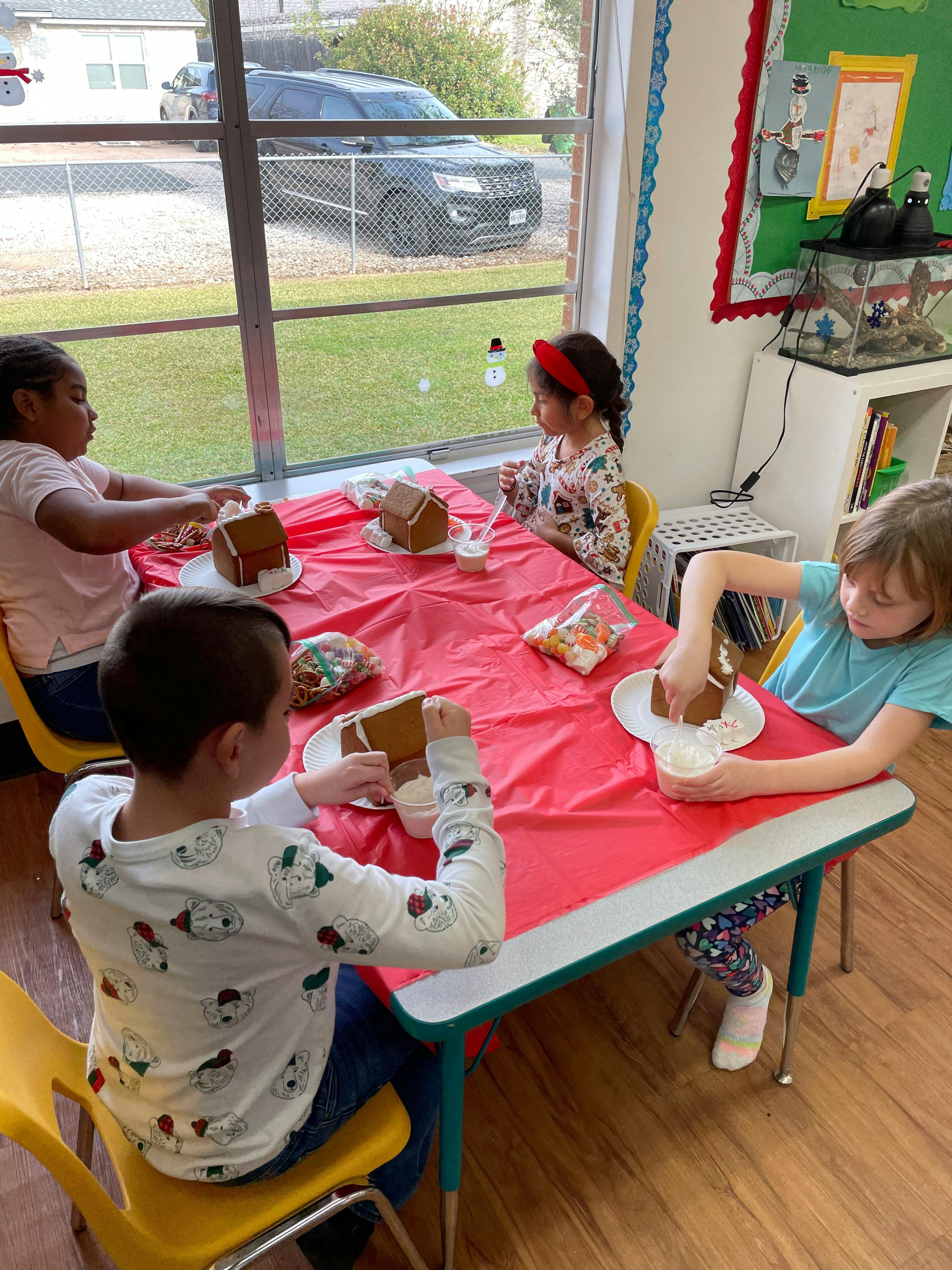 Children decorating gingerbread houses at a table