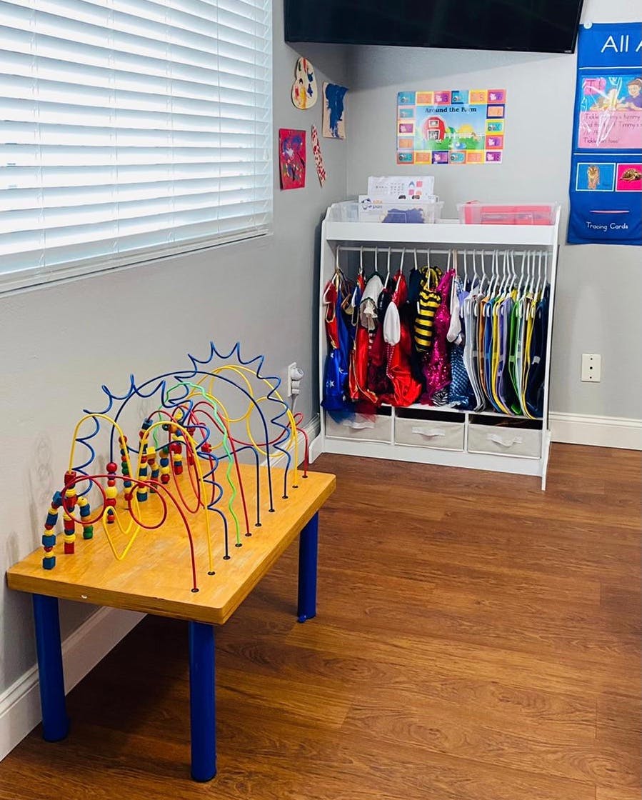 Bead maze toy on a table next to a clothing rack with costumes