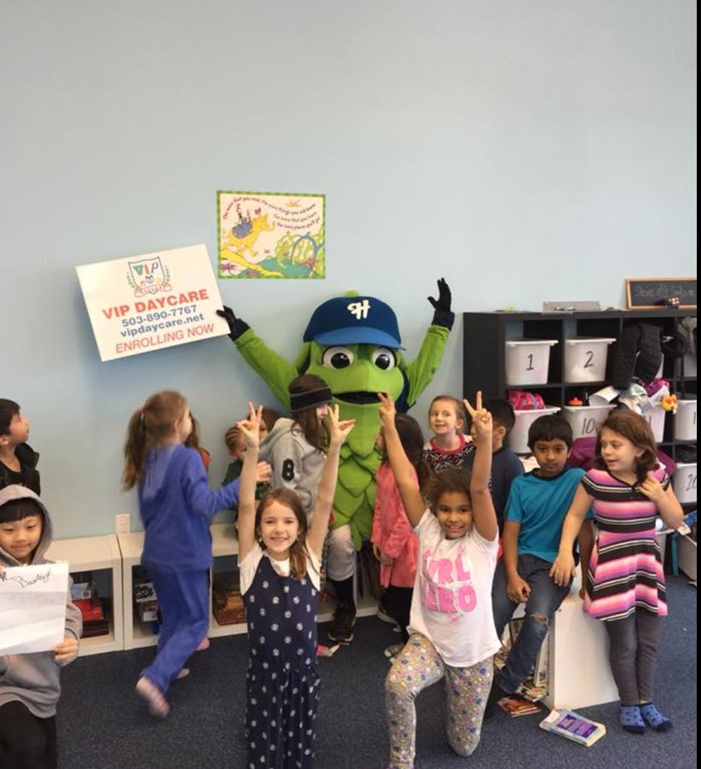 Mascot in a blue hat with children raising their arms