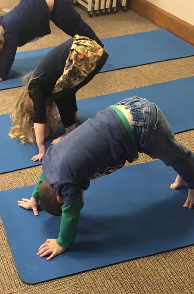 Two children on blue yoga mats in a downward dog pose