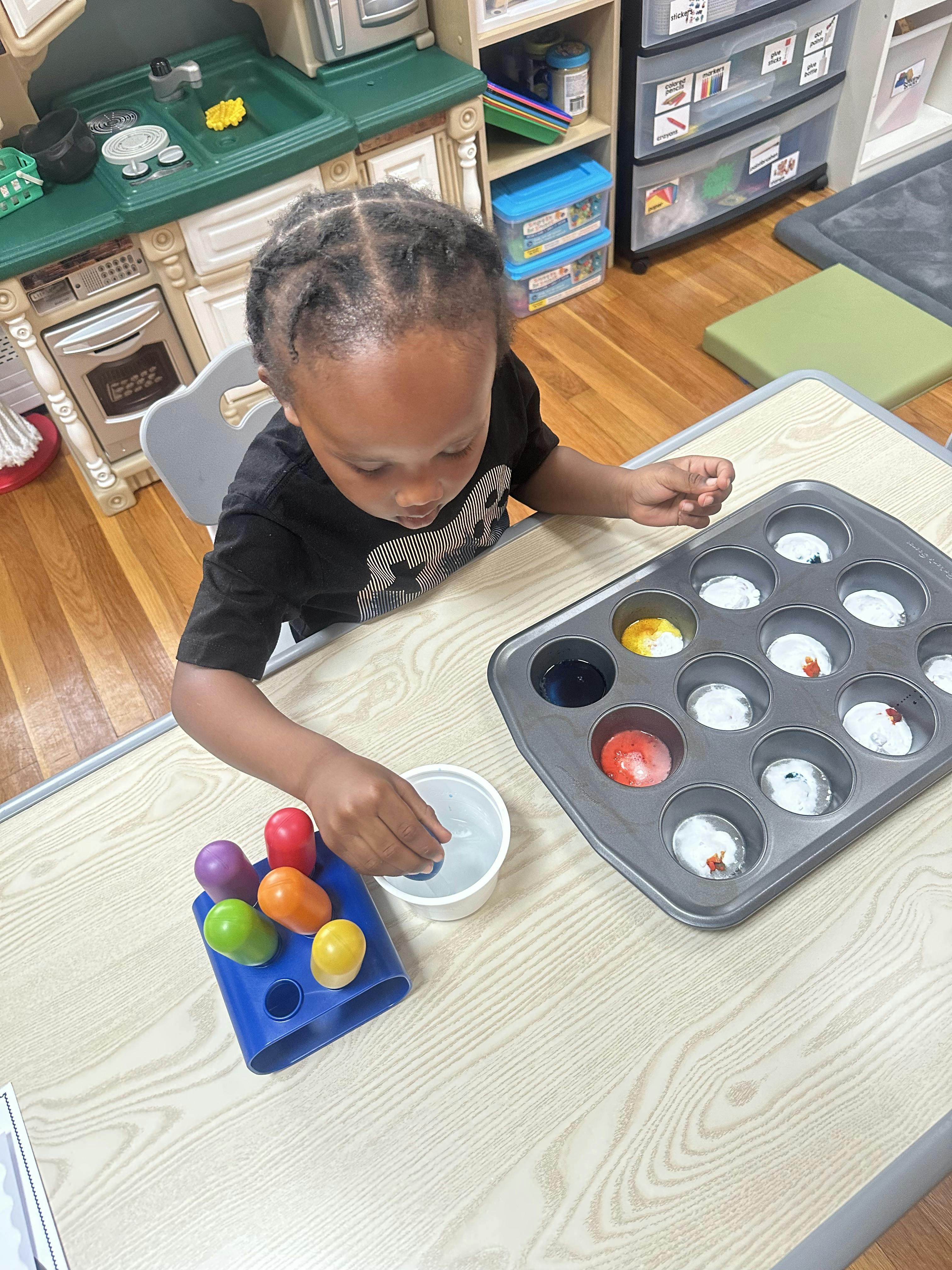 Child playing with colorful eggs and a muffin tin
