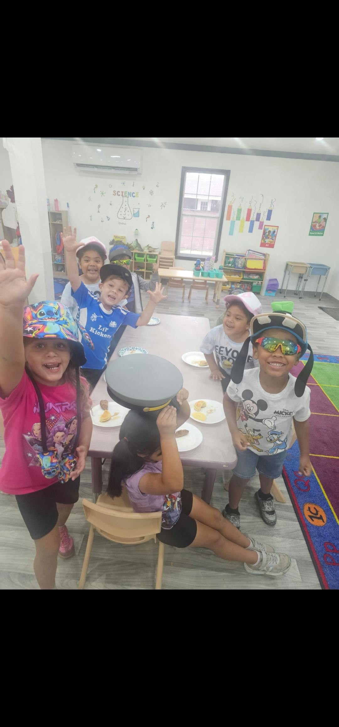 Group of children wearing hats and glasses in a classroom