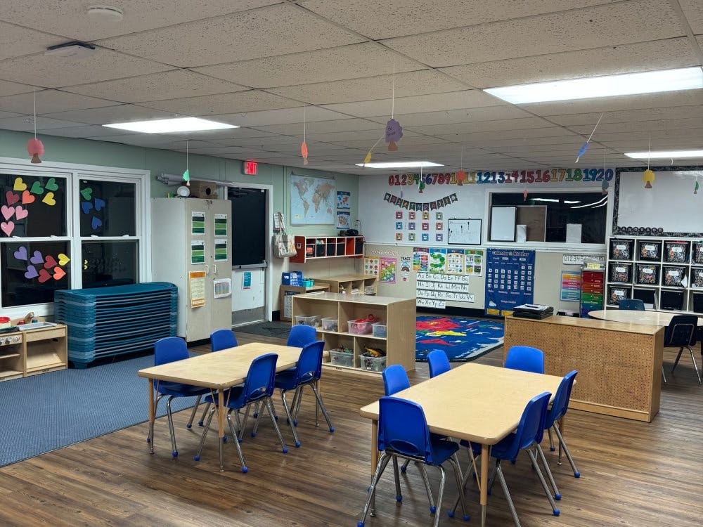 Empty classroom with small tables and chairs, and learning decorations on walls