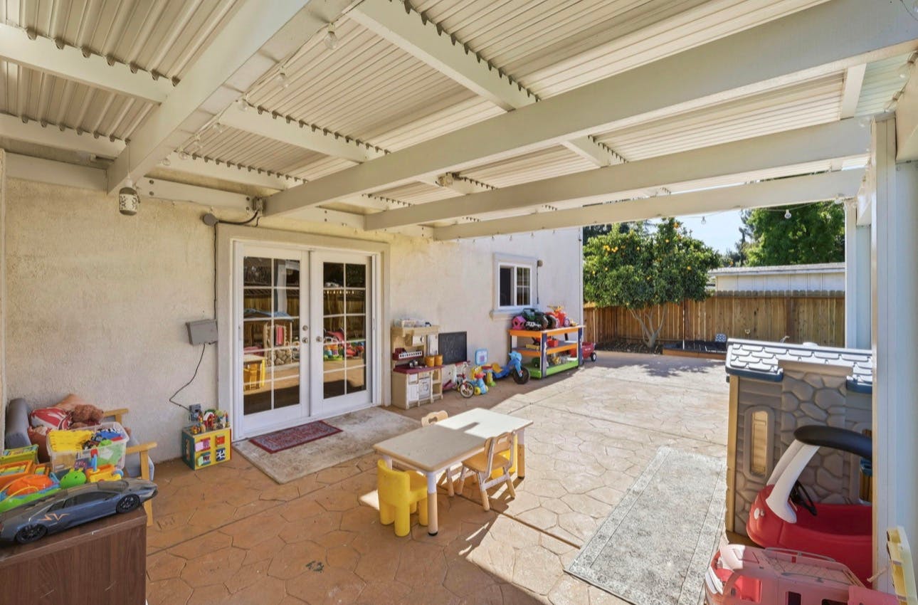 Covered backyard patio with children's toys and table
