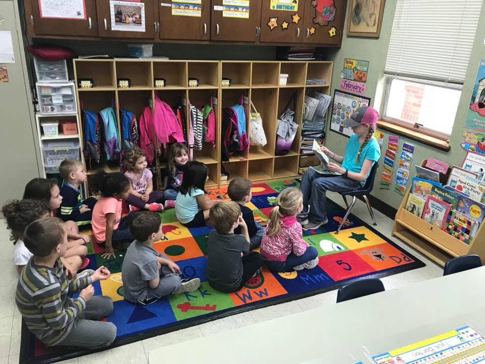 Person reading to a group of children in a classroom