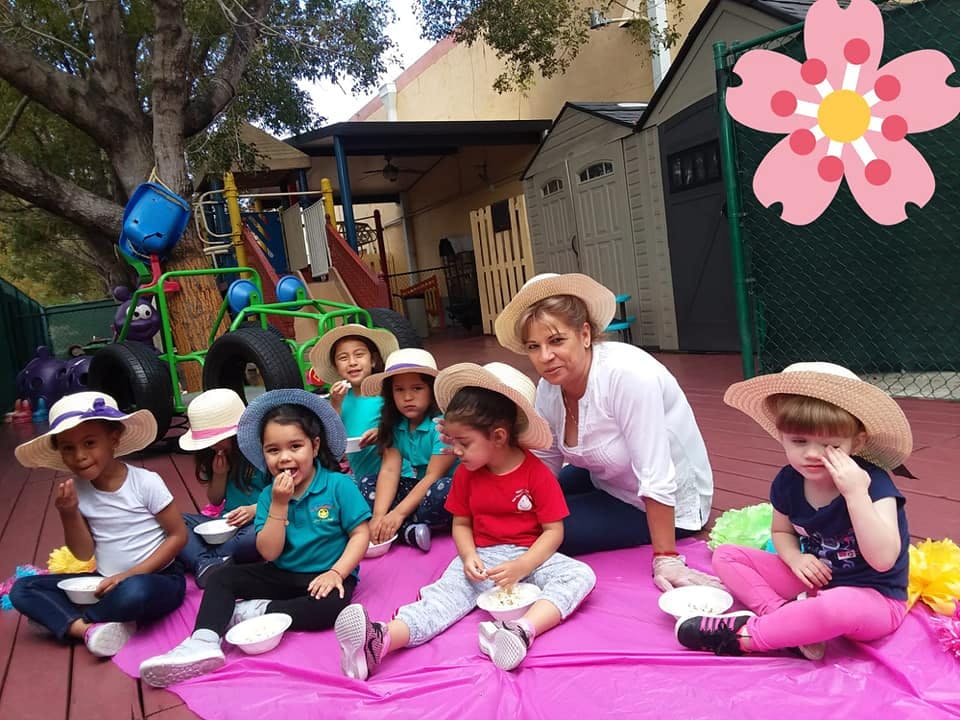 Adult and children wearing hats sitting on a blanket outdoors