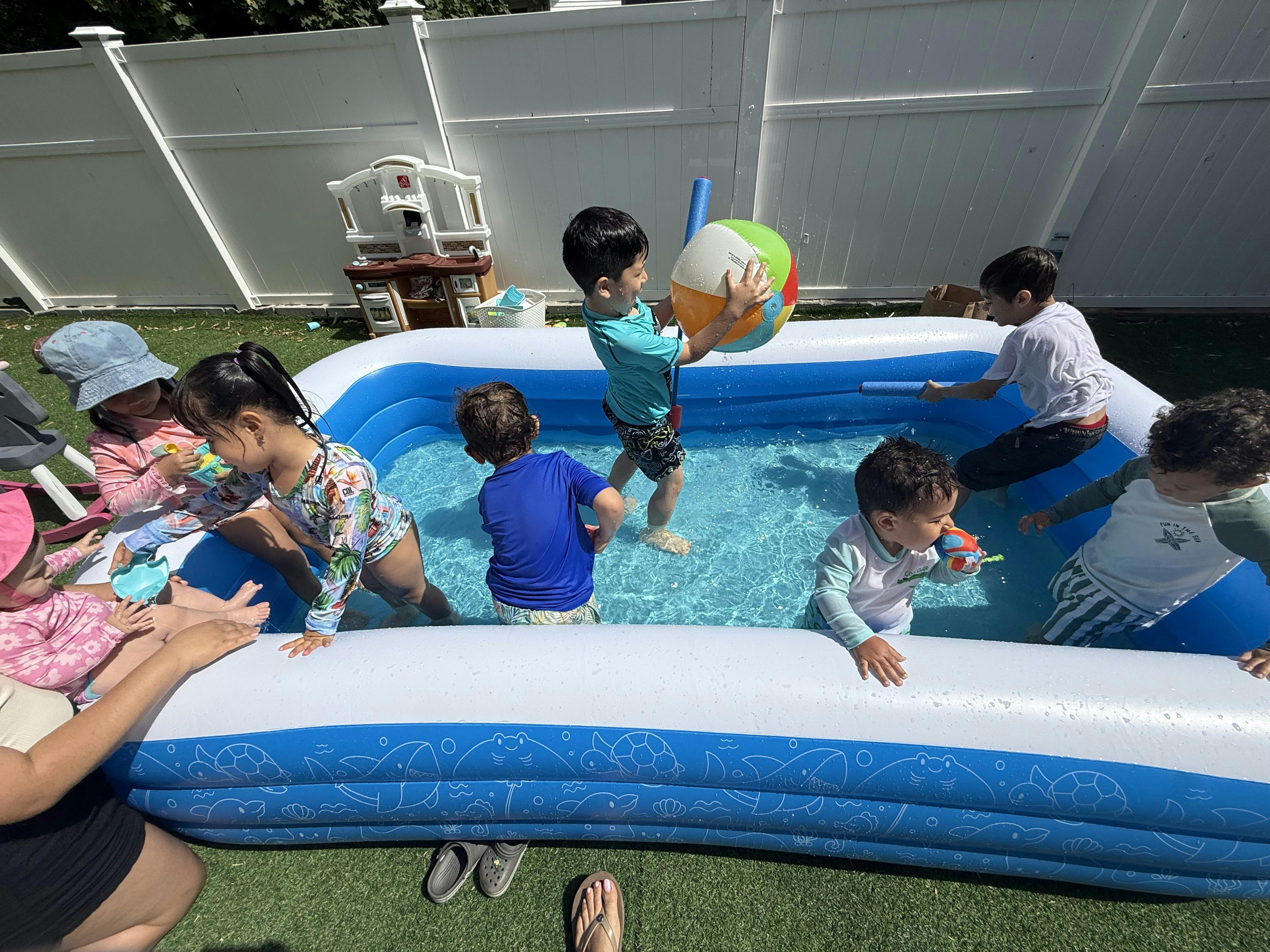 Children playing in a small inflatable pool in a yard