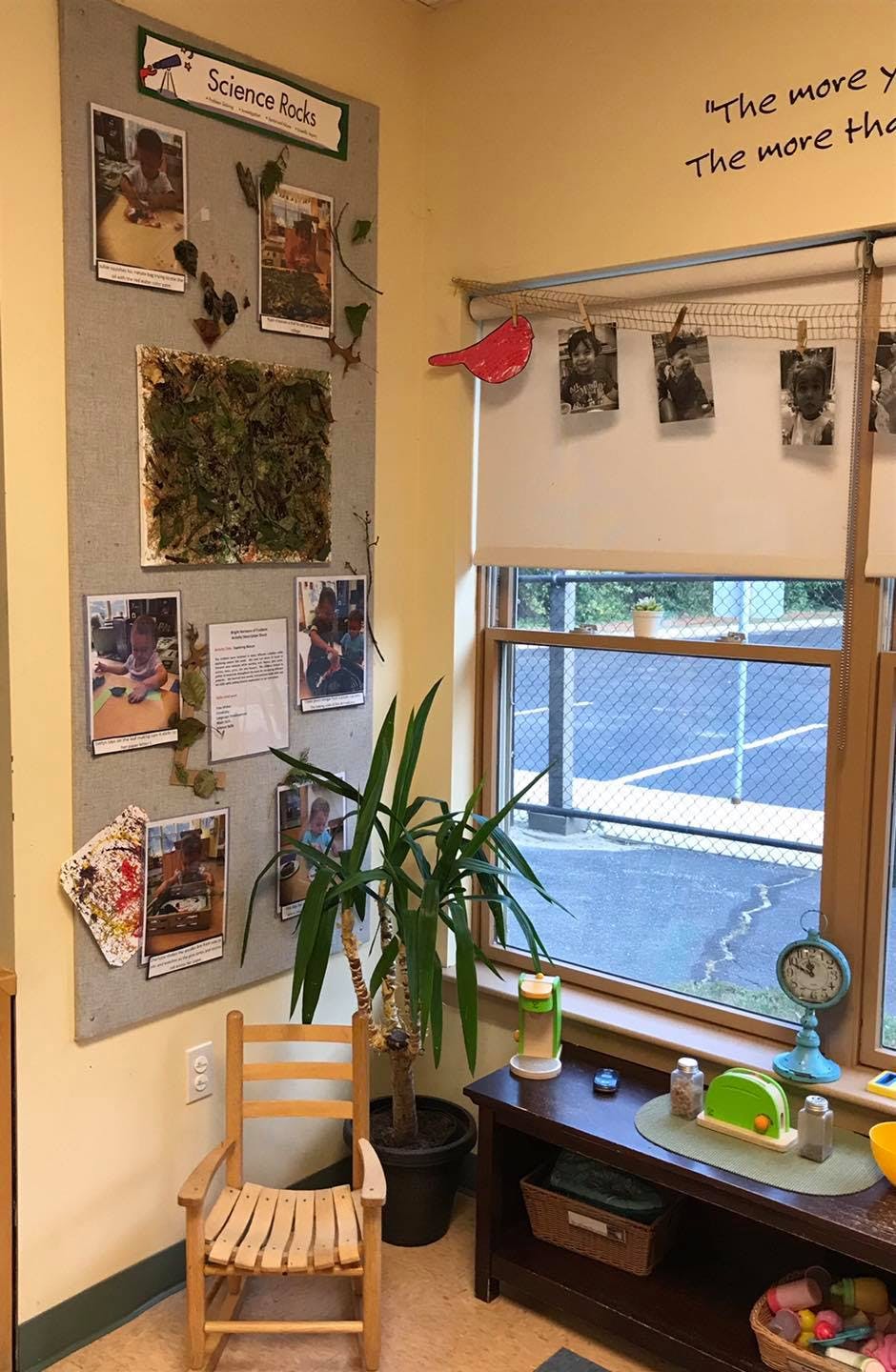 Classroom corner with bulletin board, plant, small chair, and window