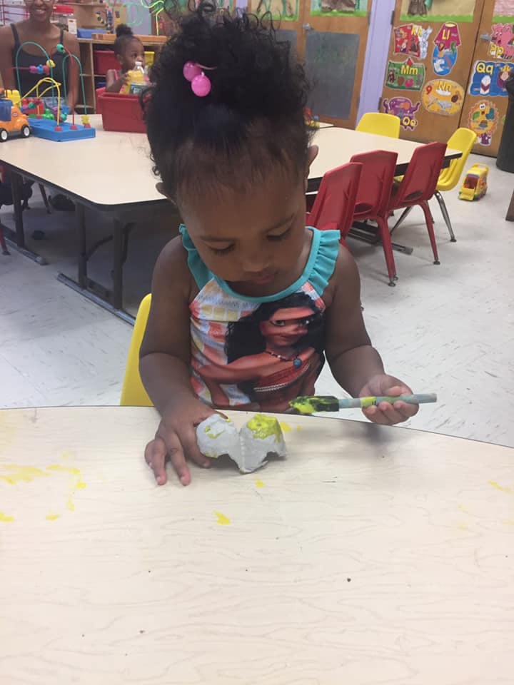 Child painting an egg carton at a table