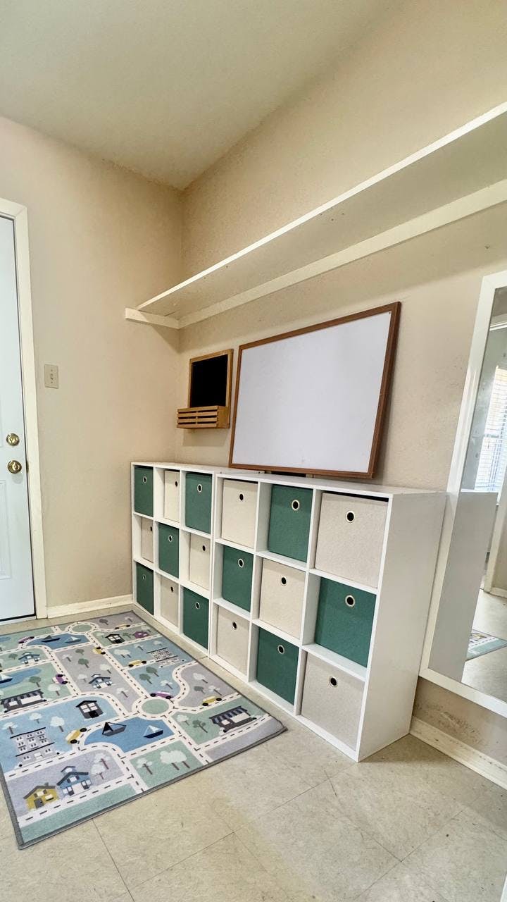 White storage unit with green and white bins, whiteboard, and playmat