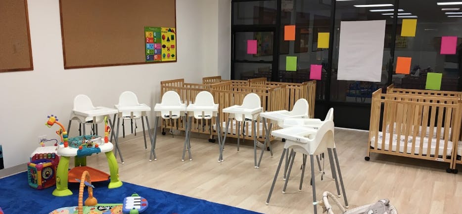 Nursery room with multiple cribs, high chairs, and infant play equipment