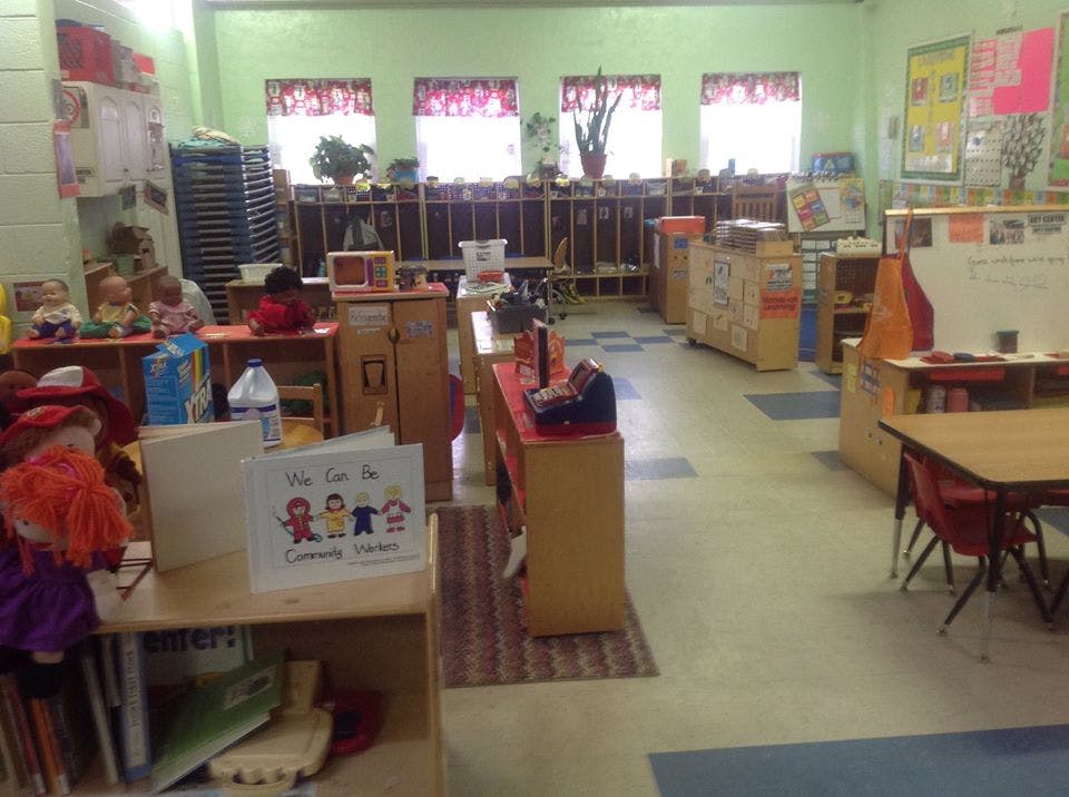 Classroom with tables, chairs, and shelves with learning materials
