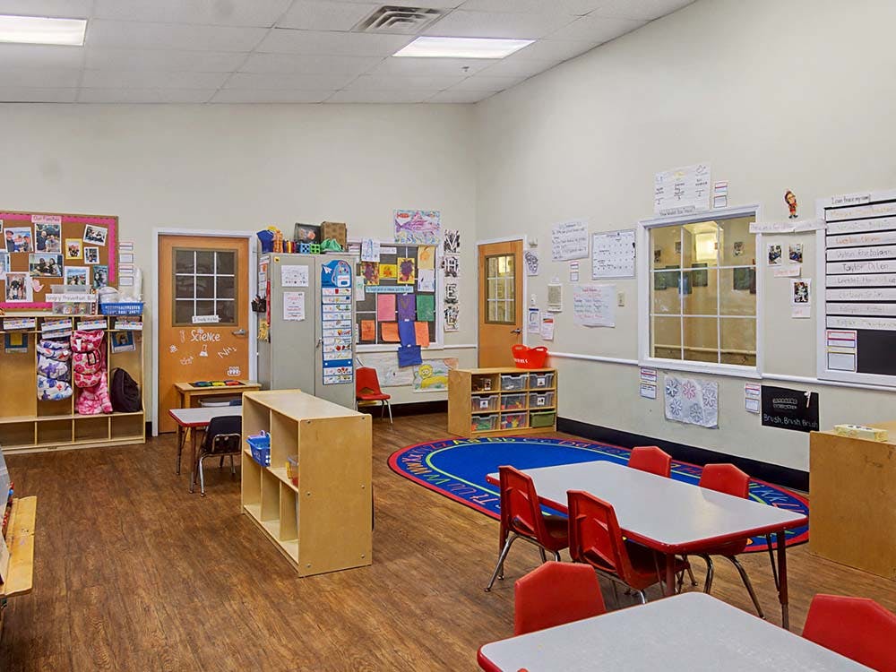 An empty early childhood classroom with small tables and chairs