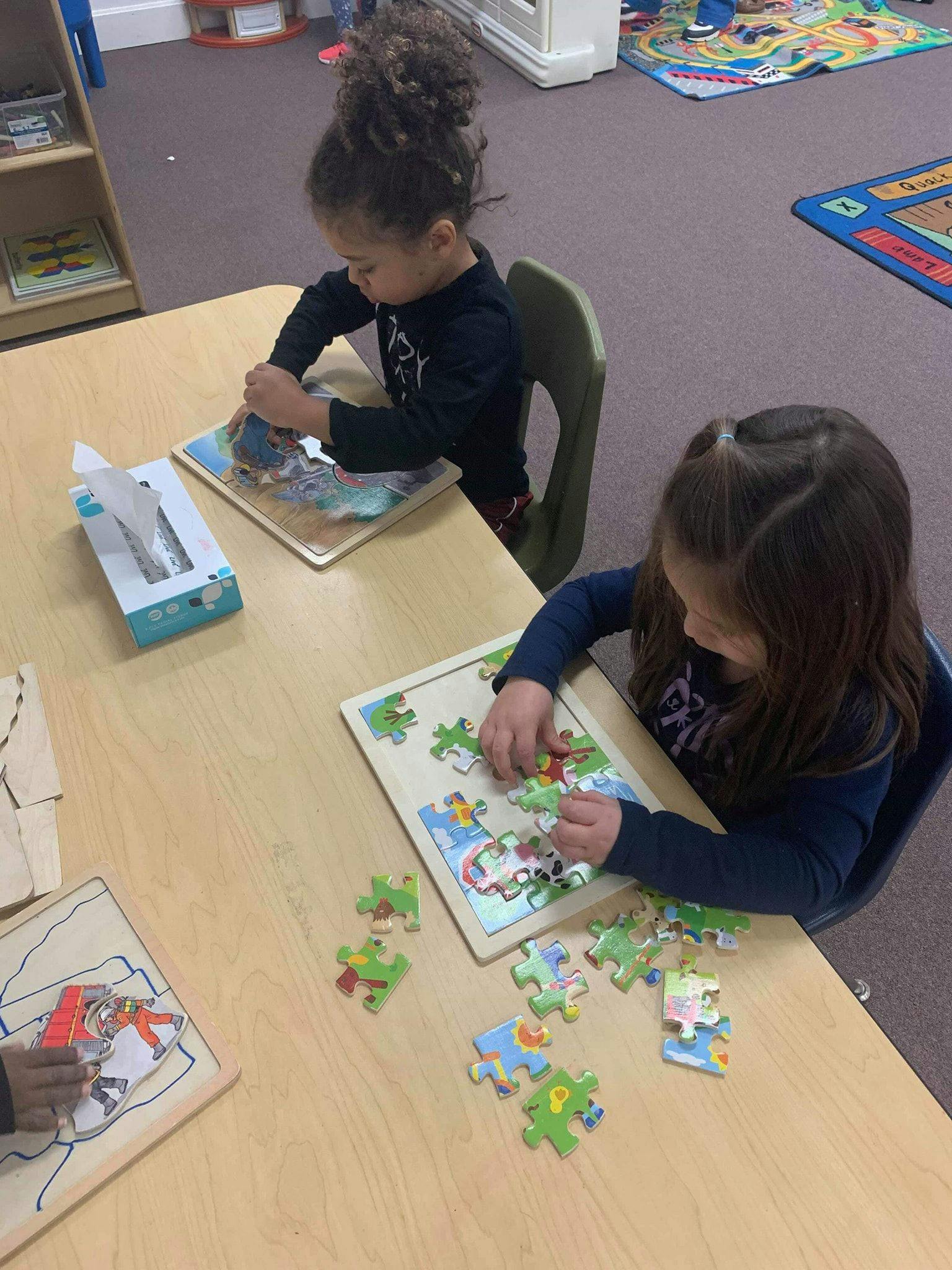 Two children playing with puzzles at a table