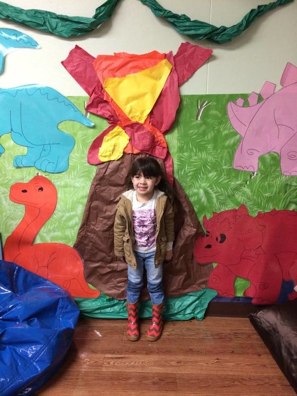 Child standing in front of a dinosaur-themed wall decoration