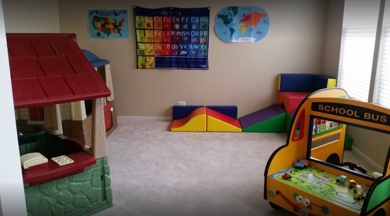 Playroom with a playhouse, soft play equipment, and a toy school bus