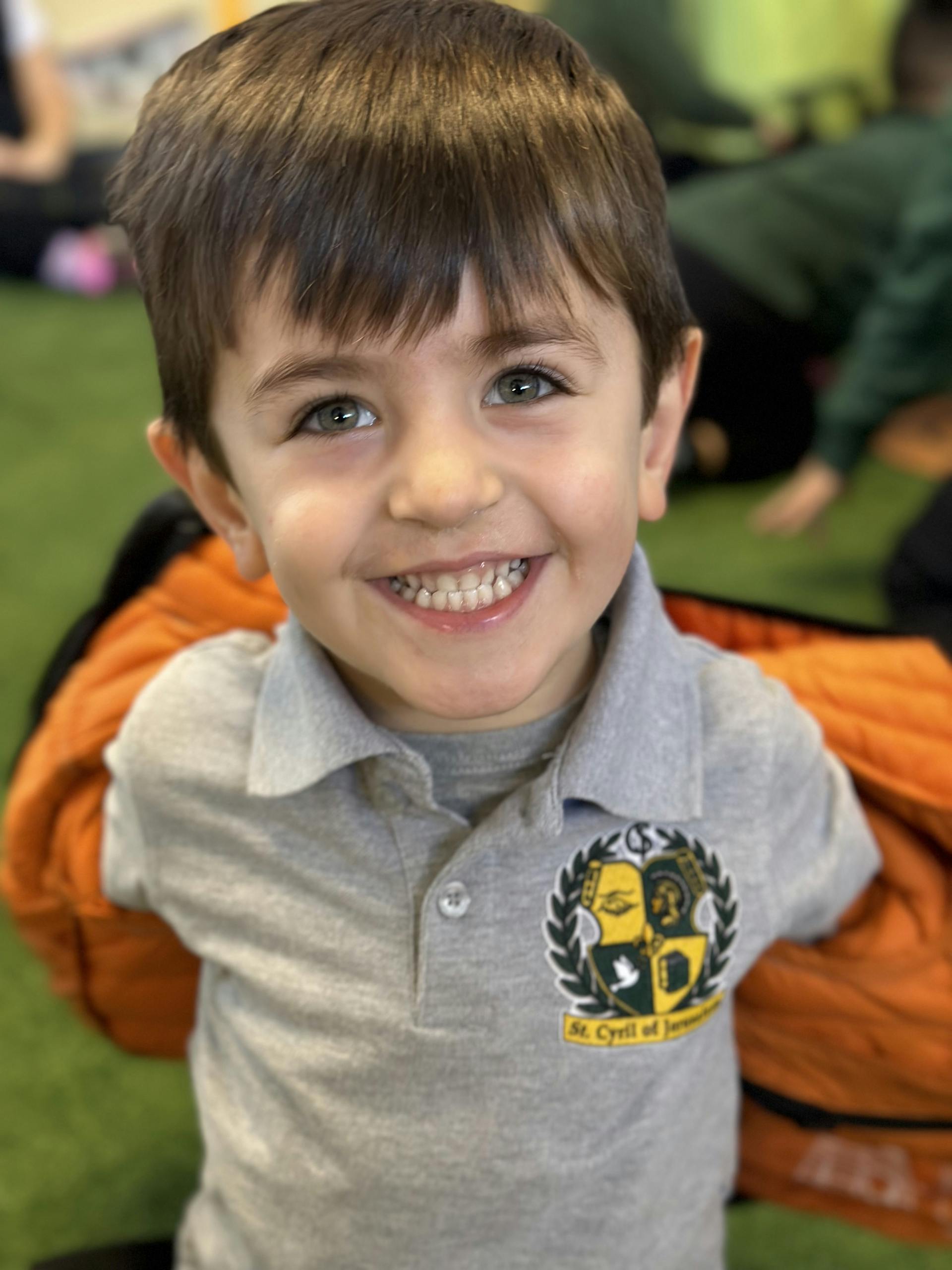 Smiling child in a gray collared shirt with a St. Cyrill of Jerusalem logo